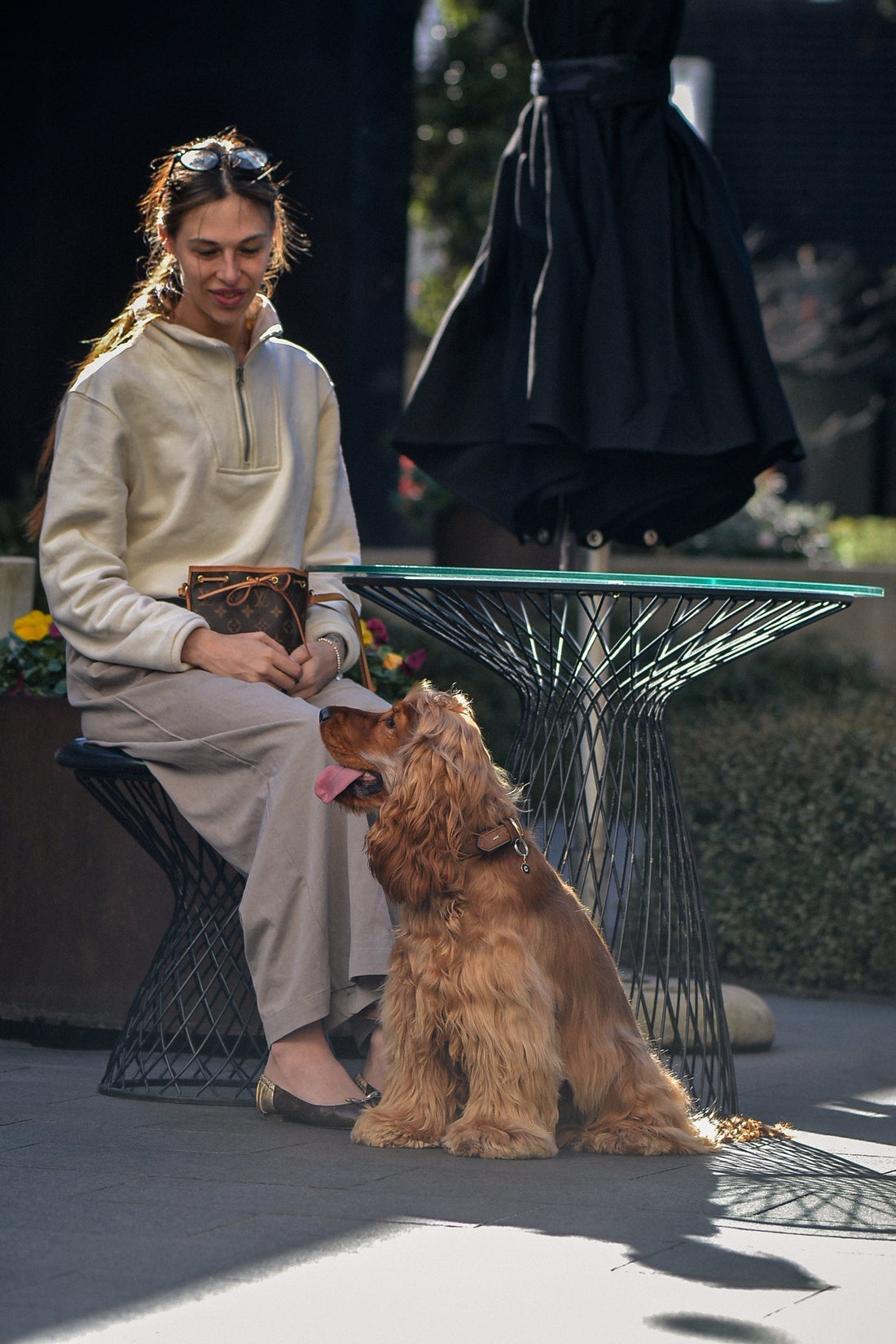 Woman and her dog sit at a sunny downtown cafe. Dog is wearing a 9ct yellow gold round pendant with natural white diamond flush-set initial.