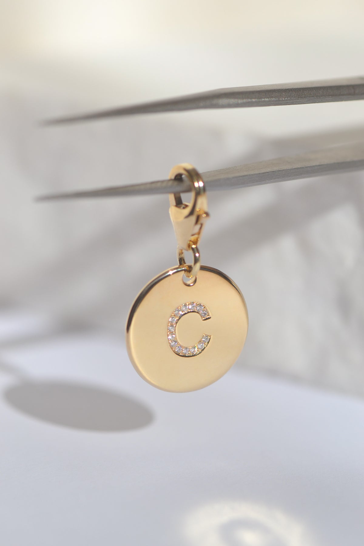 ÉMINENCE by PAWVÉ . Fine Jewellery for pets. ÉMINENCE a solid 9ct yellow gold pendant, with flush set natural white diamonds to form pets initial. Photographed on a white neutral background.