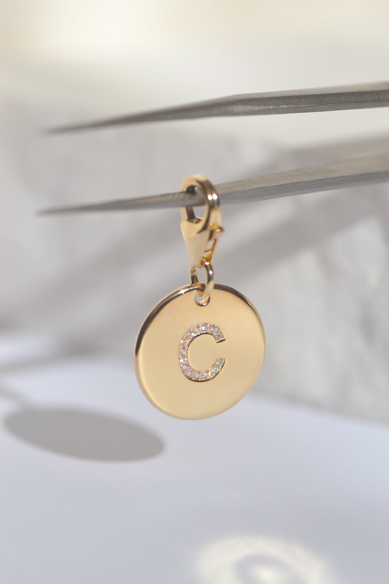 ÉMINENCE by PAWVÉ . Fine Jewellery for pets. ÉMINENCE a solid 9ct yellow gold pendant, with flush set natural white diamonds to form pets initial. Photographed on a white neutral background.